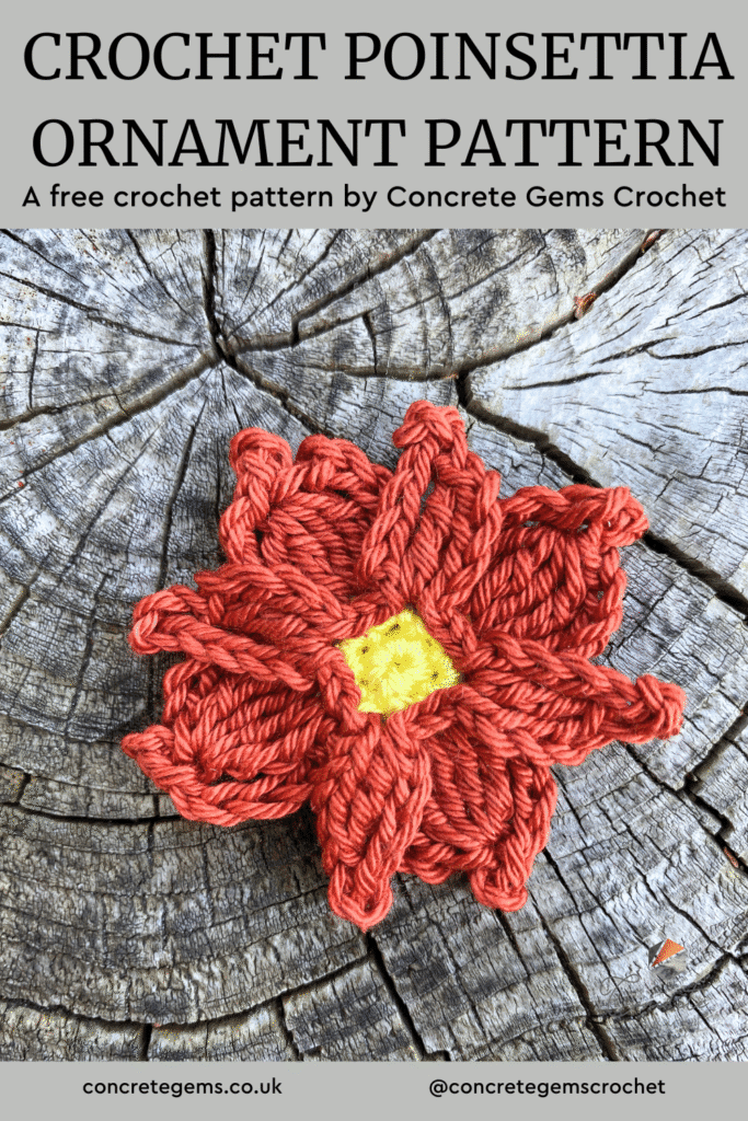 A crochet poinsettia flower ornament lays on a wooden surface
