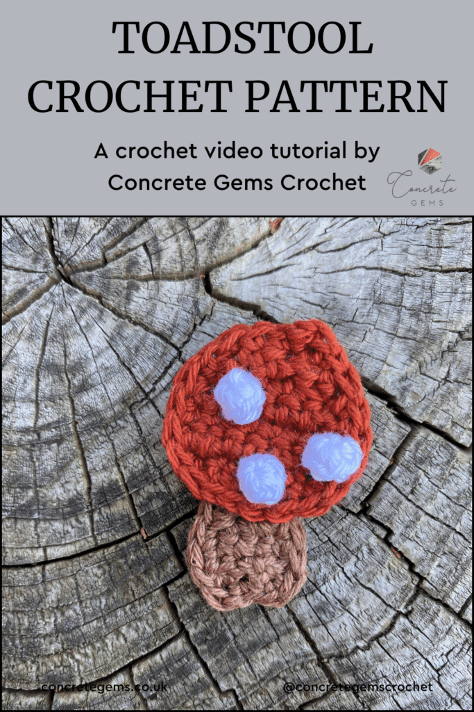 A crochet toadstool motif lies on a wooden slice with the words TOADSTOOL CROCHET PATTERN above