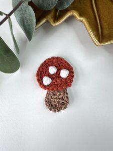 A crochet mushroom applique with red cap and white spots