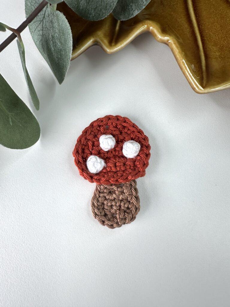 A crochet mushroom applique with red cap and white spots
