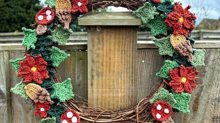 A rattan wreath with crochet woodland motifs hangs on a fence