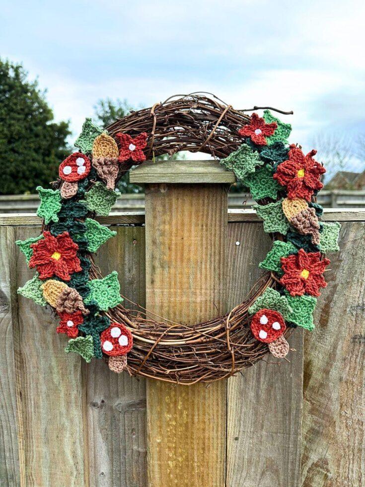 A rattan wreath with crochet woodland motifs hangs on a fence