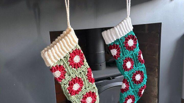 2 crochet stockings made of granny squares that look like red poinsettias or a green background hang on a mantelpiece