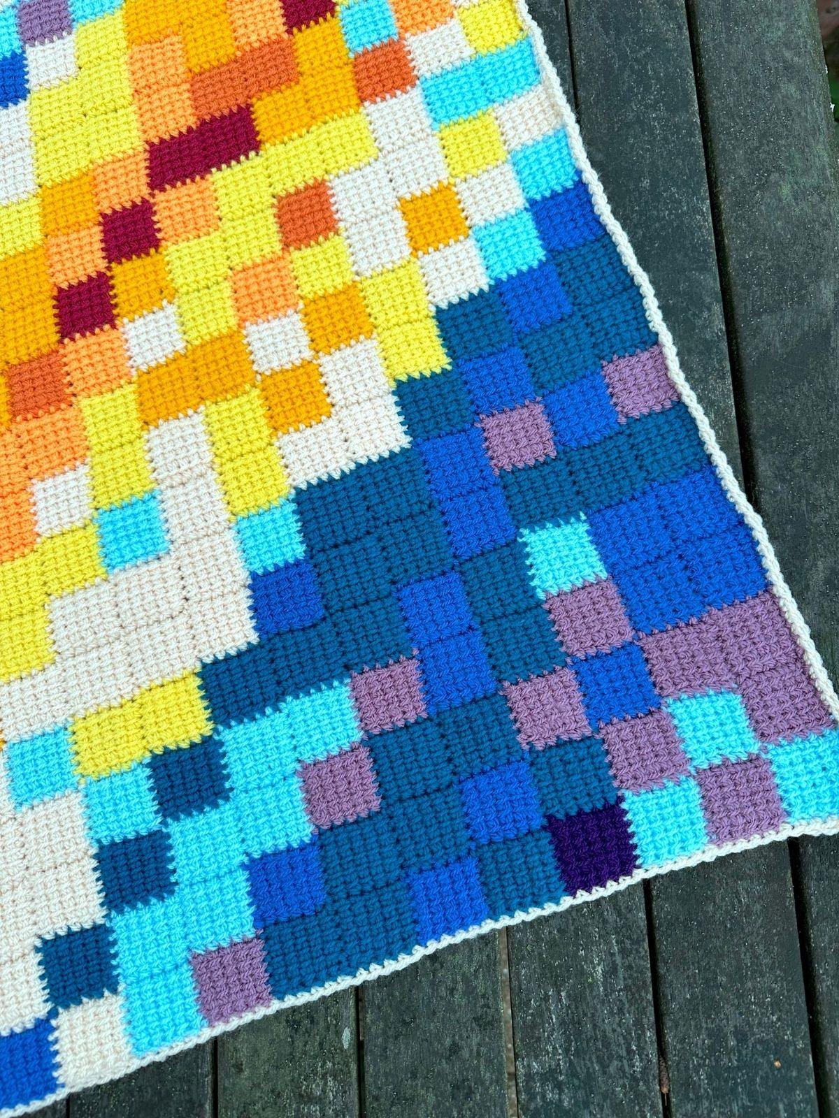 Close up of a triangle shaped Tunisian Crochet Shawl laid out on a wooden table