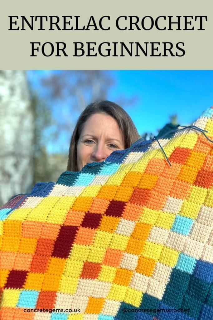 A photo of a lady holding up a crochet shawl which is covering most of the face and the words ENTRELAC CROCHET FOR BEGINNERS above. The shawl is multi-coloured made from small squares of Tunisian Crochet