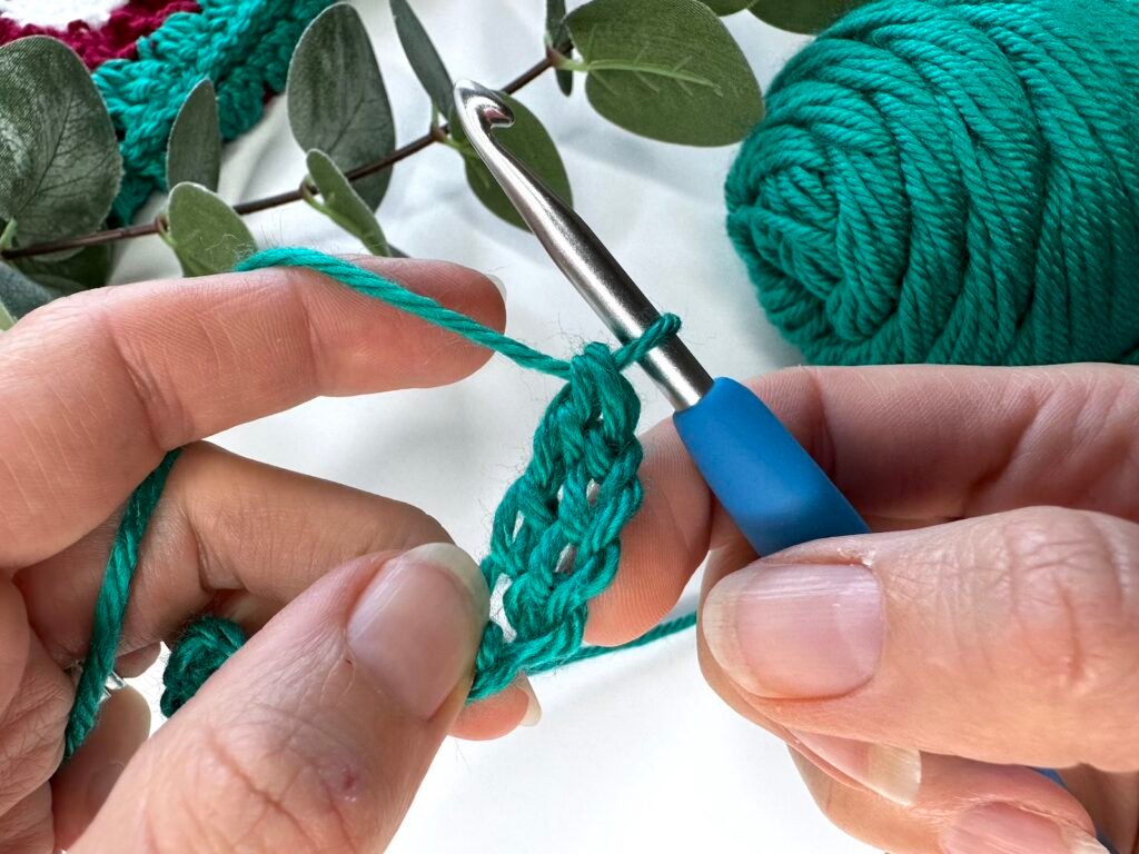 2 hands hold a piece of crocheted fabric showing a completed treble crochet stitch