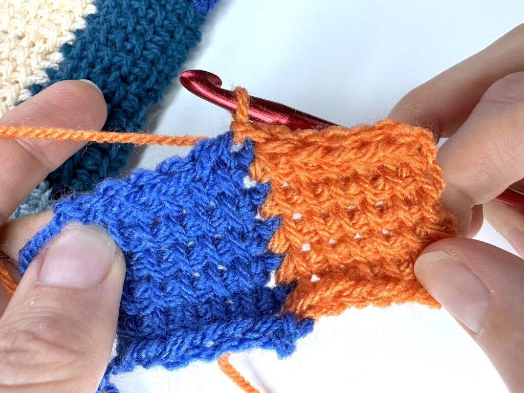 A Tunisian crochet entrelac initial square completed and held in 2 hands