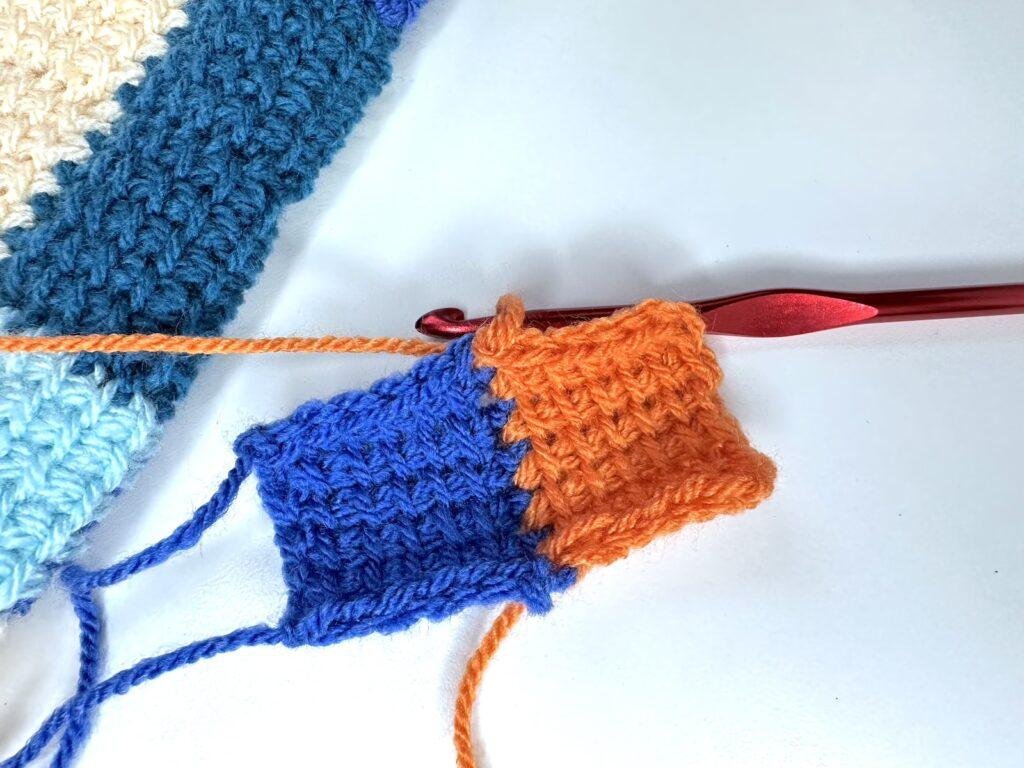 A sample of tunisian crochet entrelac showing a blue first square and a orange initial square next to a larger sample of entrelac