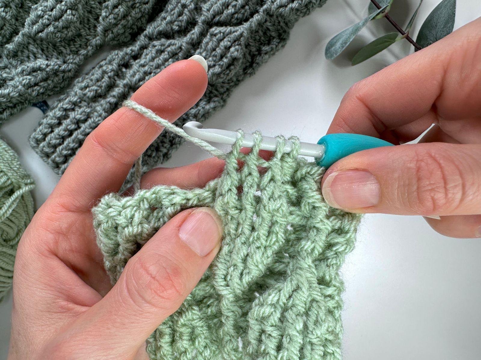 2 hands show a crochet sample of a part completed front post double crochet 3 together stitch