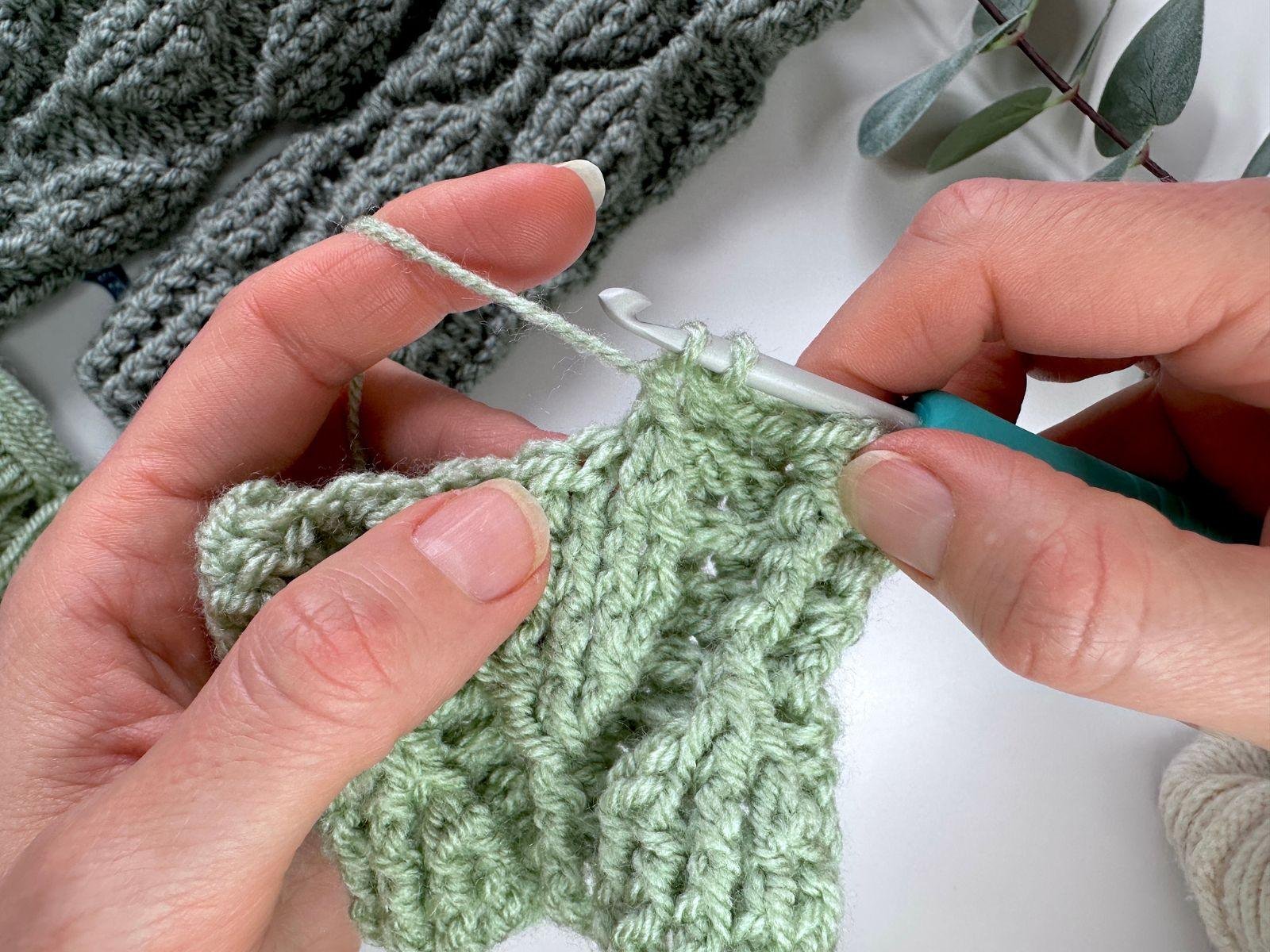 the start of a front post double crochet stitch 3 together is shown on a green crochet sample