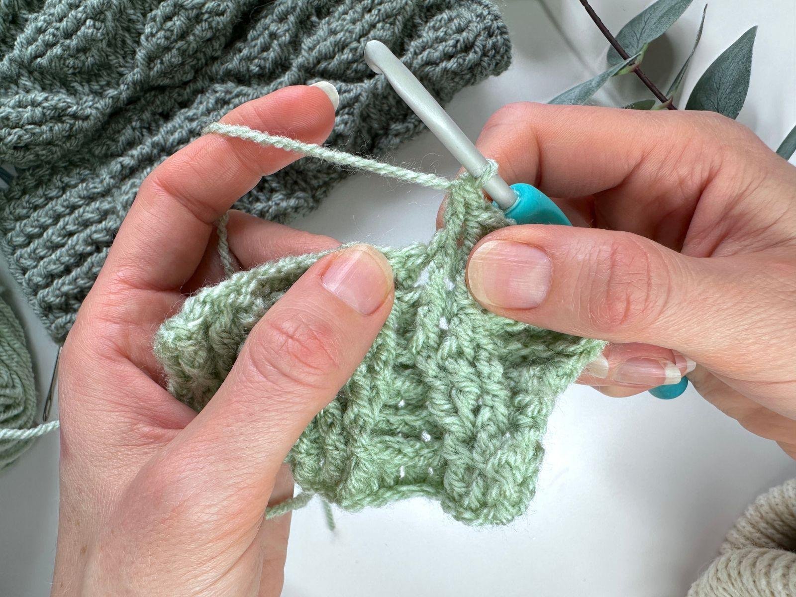 2 hands are crocheting front post double crochet stitches around previous post stitches