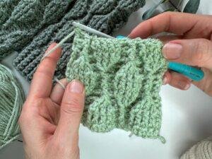 A sample of the trailing leaves crochet stitch pattern held in 2 hands with other crochet in the background.