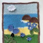 A spring crochet scene of the sea, rocks, flowers and birds