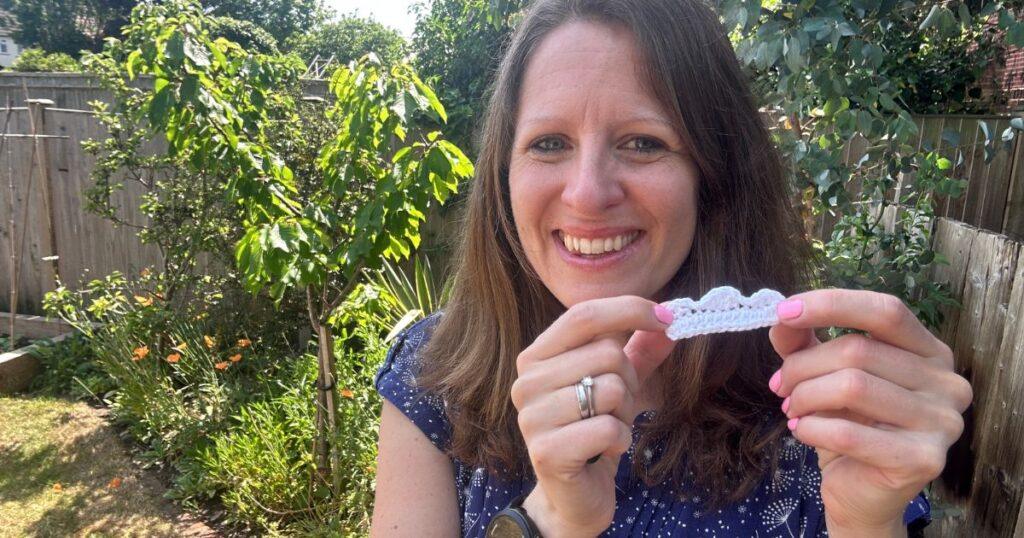 A lady holds a small white crochet cloud in her hands