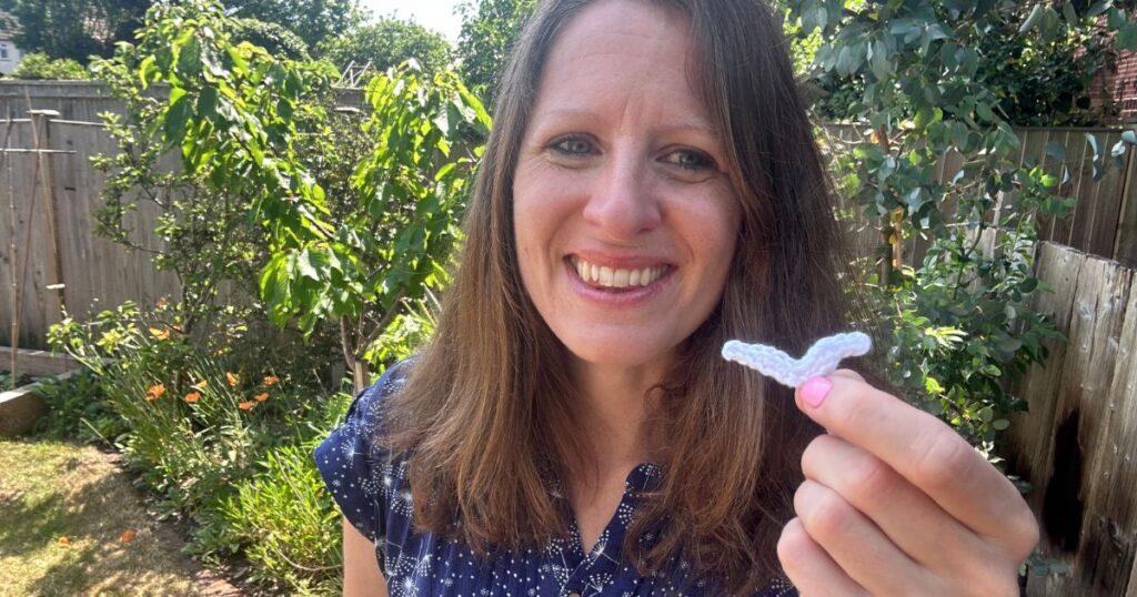 A lady holds a tiny crochet seagull applique in her hand