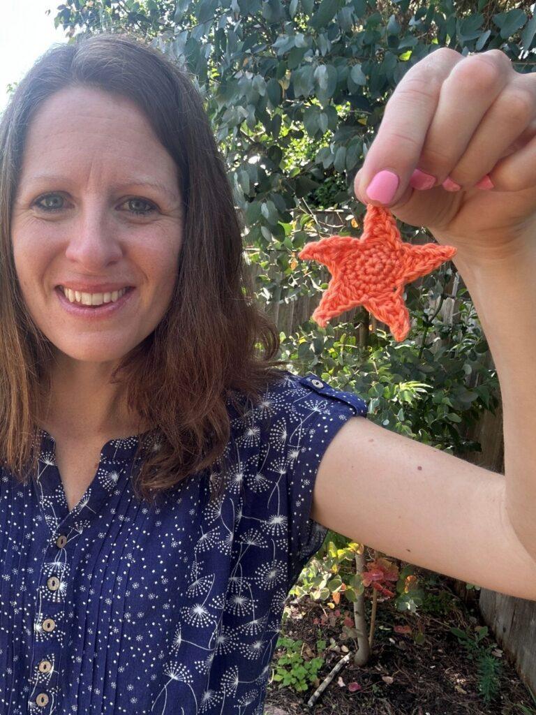 A woman holds up a small crochet starfish