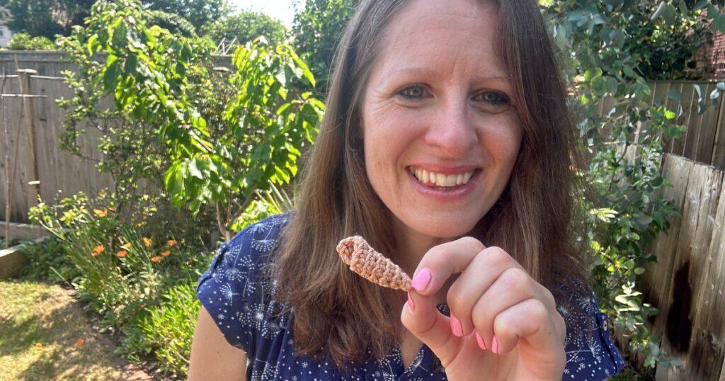 A lady holds a small twisty crochet conch shell