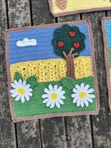 A crochet picture of summer fields , wheat fields, tree and flowers