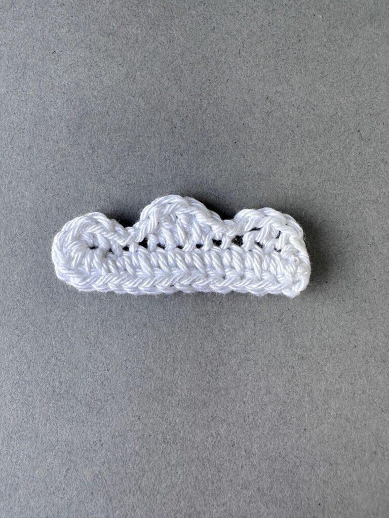 A white crochet asymmetrical cloud on a grey background