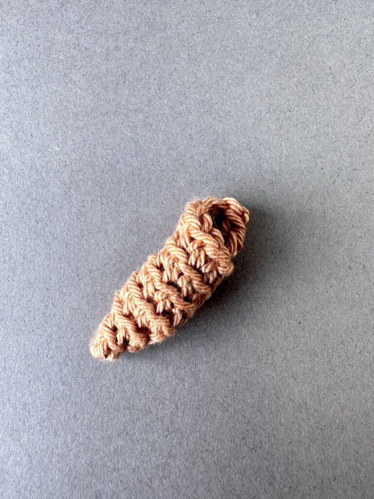 A beige crochet conch shell on a grey background