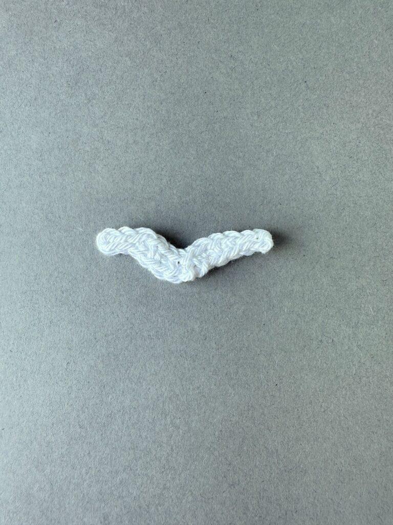 A white crochet seagull applique on a grey background