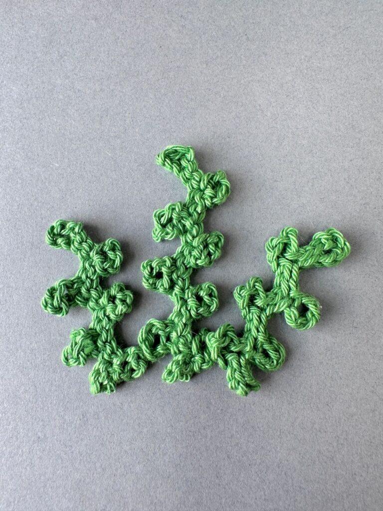 Green crochet seaweed on a grey background