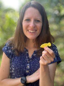 A lady holds a small free crochet fish pattern