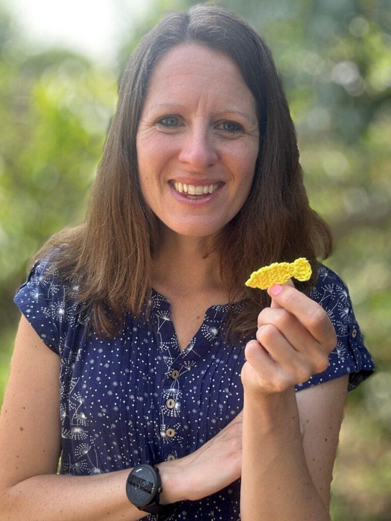 A lady holds a small free crochet fish pattern