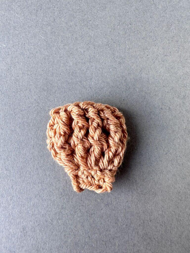 A beige crochet scallop shell on a grey background
