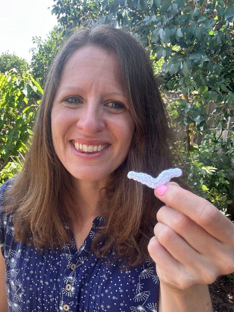 A lady holds a small crochet seagull for cards and pictures