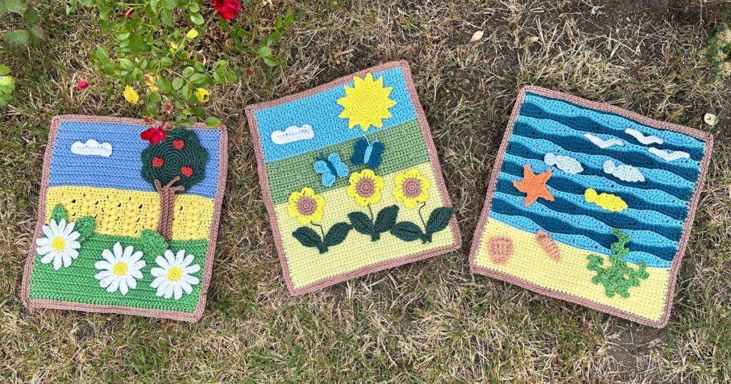 3 summer crochet landscapes are laid out on the grass, featuring trees, seaside, flowers and fields