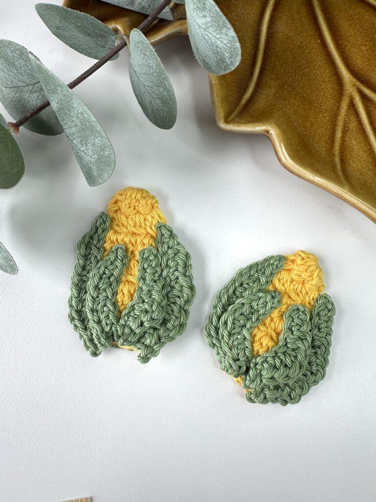 2 crochet corn on the cobs in yellow with green leaves 