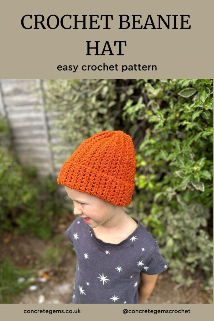 A girl stands in a garden wearing an orange crochet hat