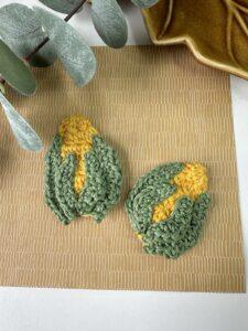 2 crochet corn on the cob appliqué motifs in yellow and green on a brown background