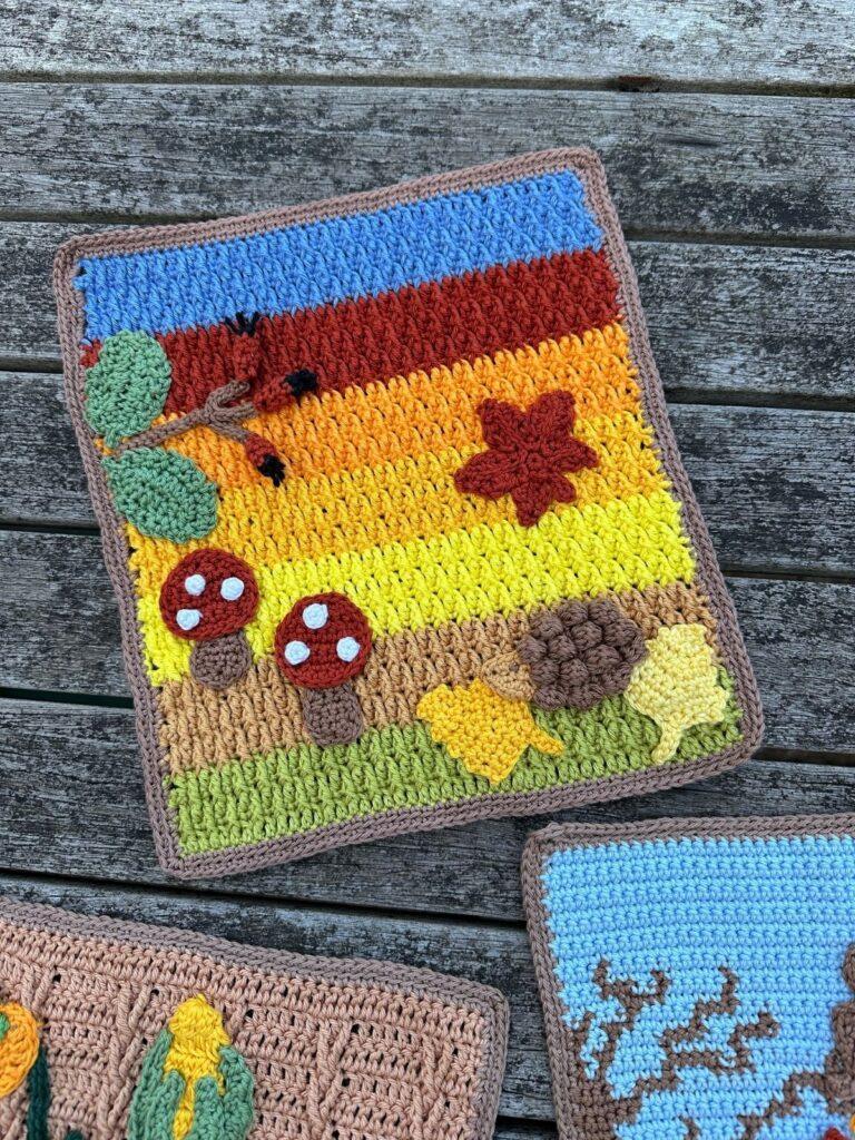 An autumn crochet picture with autumn leaves, crochet toadstool and crochet hedgehog