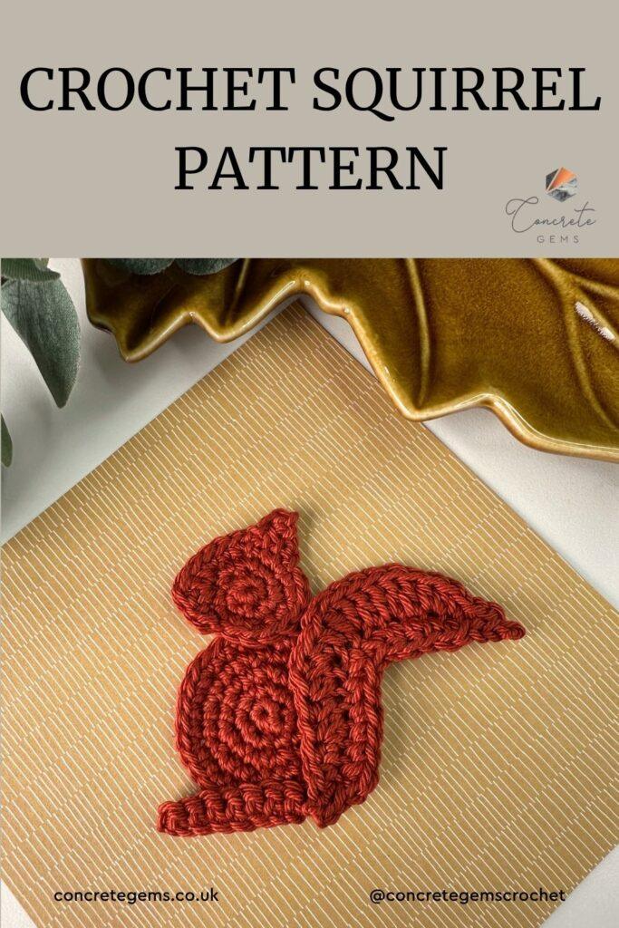 A red crochet squirrel motif on a brown paper background