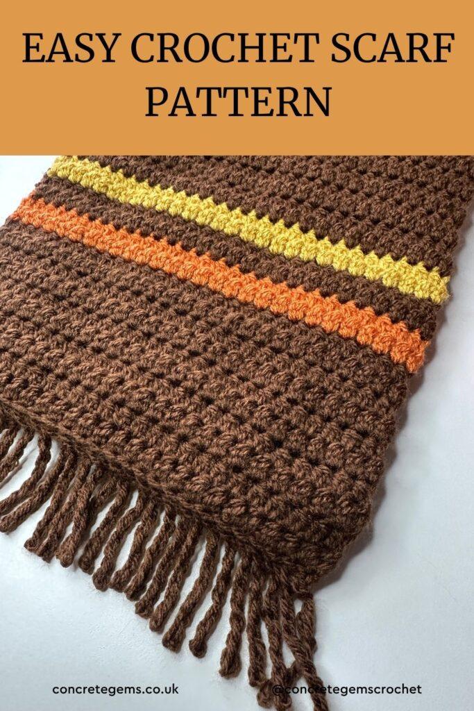 A pin with a close up of a brown scarf with a twisted fringe and yellow and orange stripe.